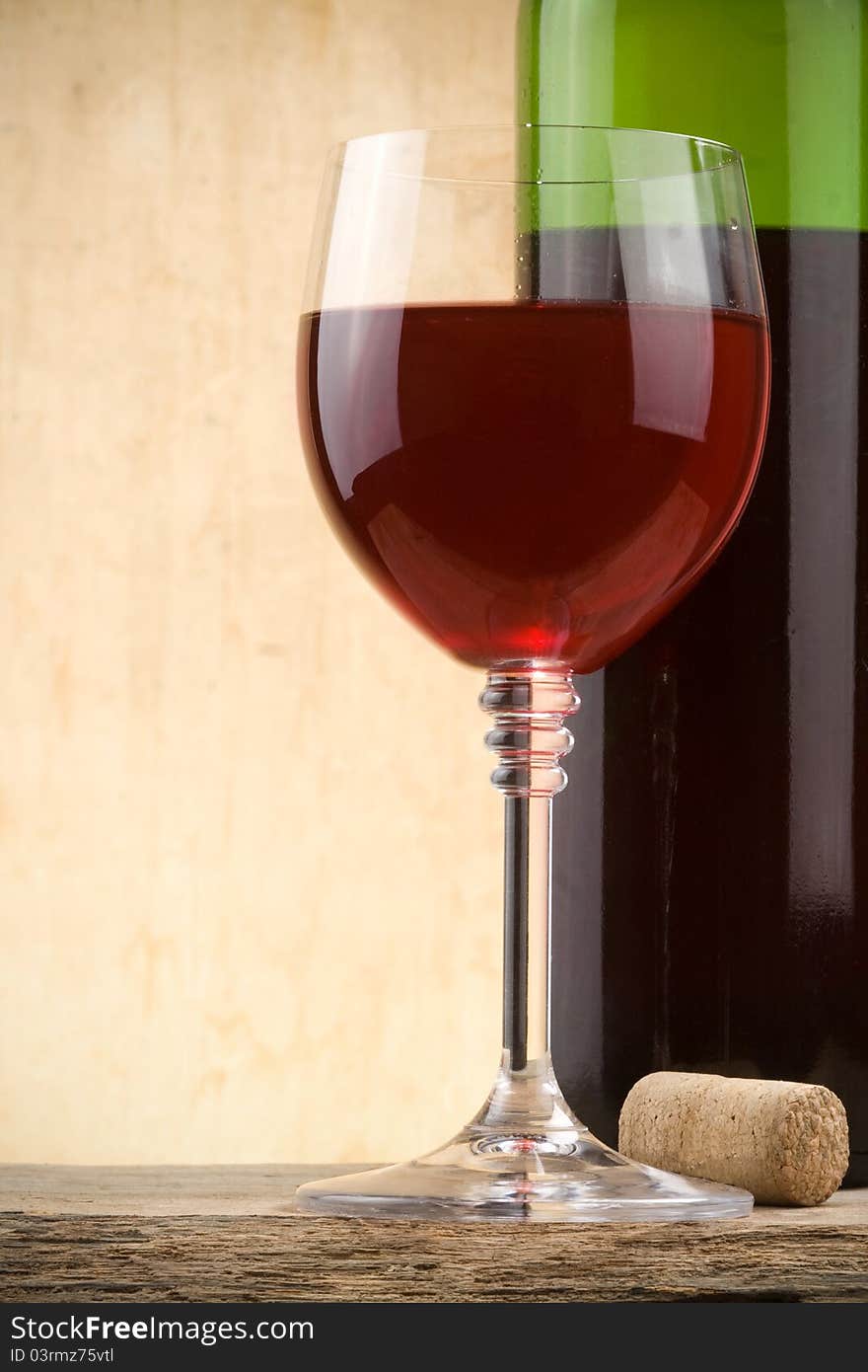 Glass of red wine and bottle on wood background