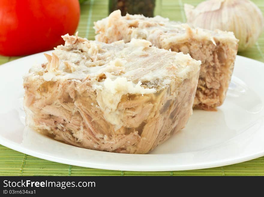 Jellied meat on a white plate against the vegetables