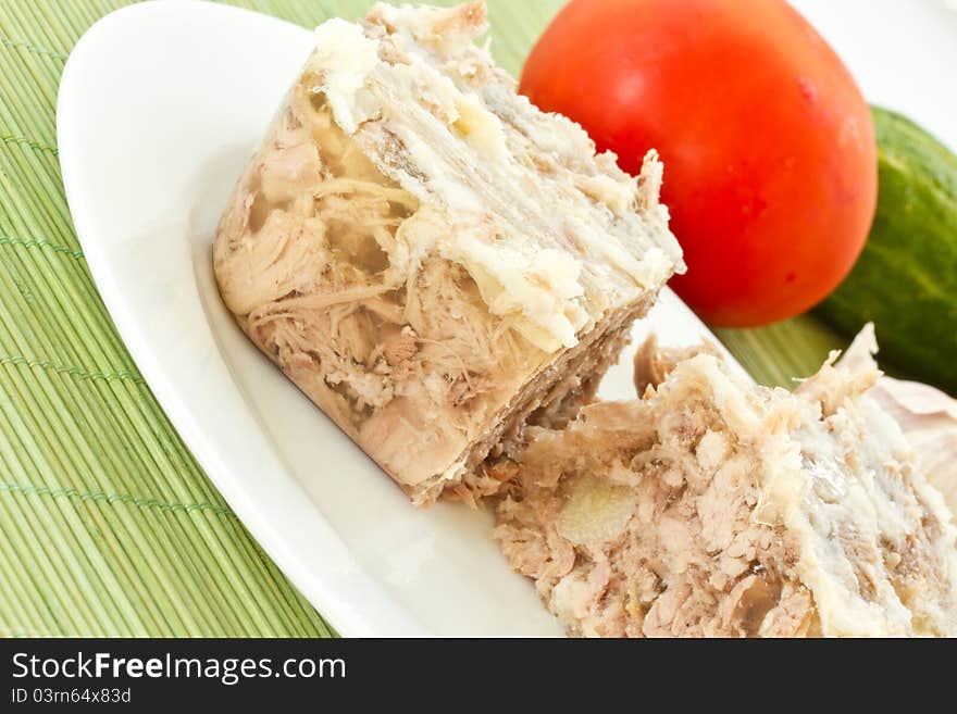 Jellied meat on a white plate against the vegetables