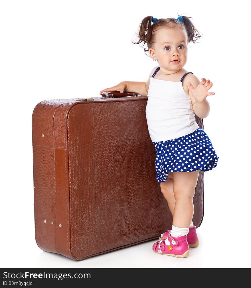 A little girl is standing near the suitcase . Isolated on a white background