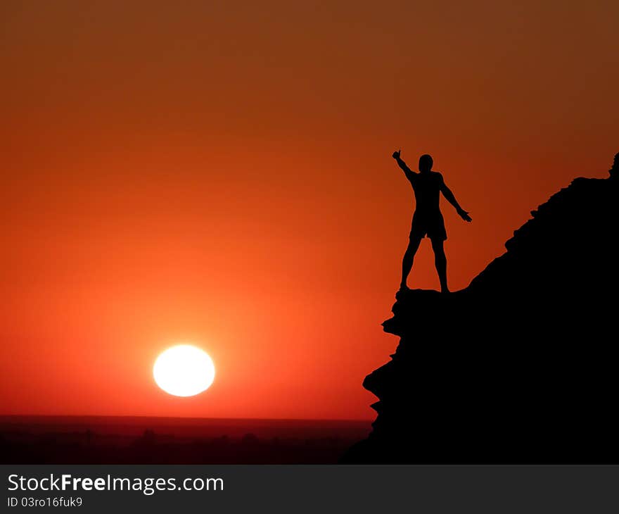 Man on top of the mountain reaches for the sun