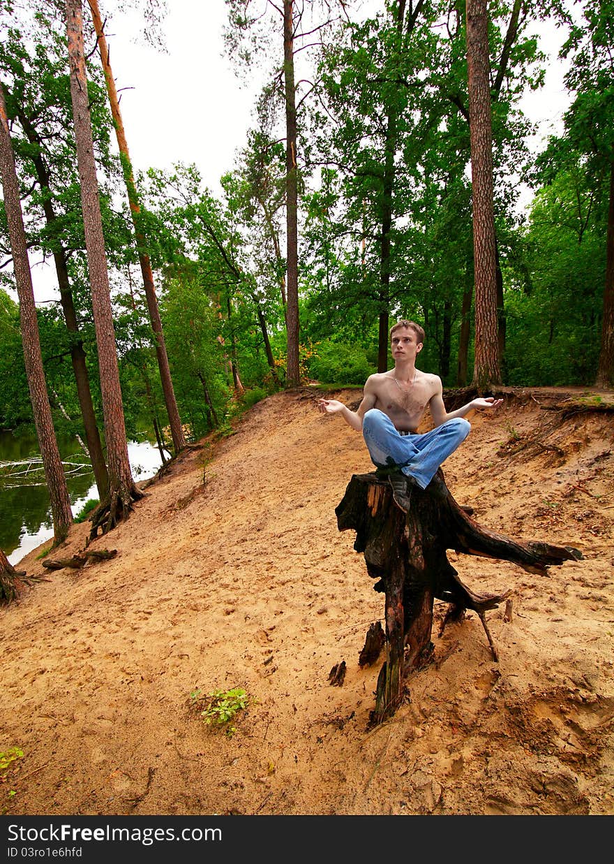 young guy meditates, sitting on a stub