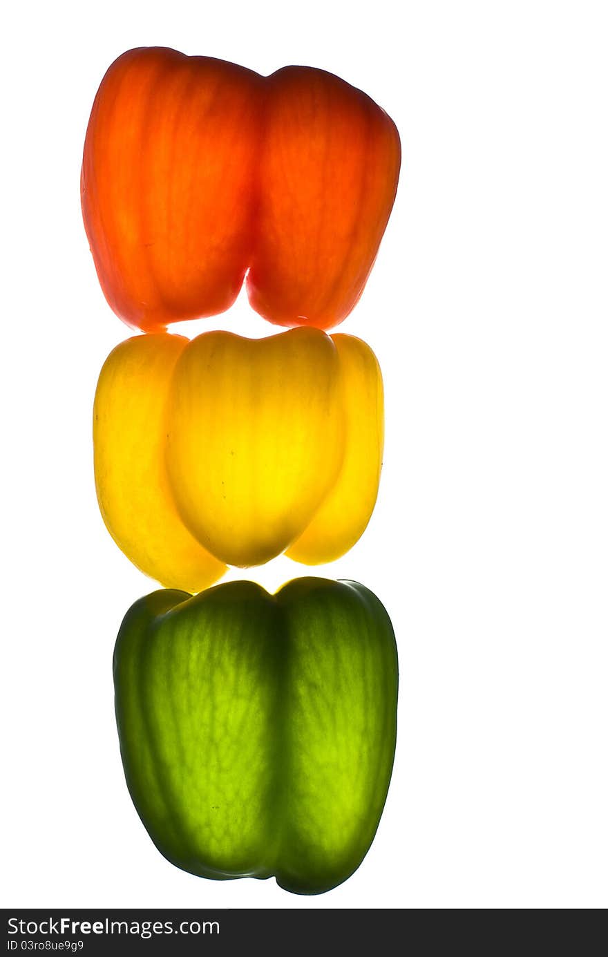 Paprika red, yellow, green on a white background illuminated from the bottom point located vertically. Paprika red, yellow, green on a white background illuminated from the bottom point located vertically