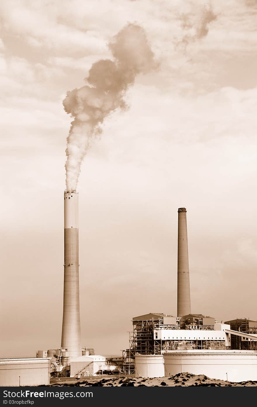 Smokestacks of power station on sky background. Sepia