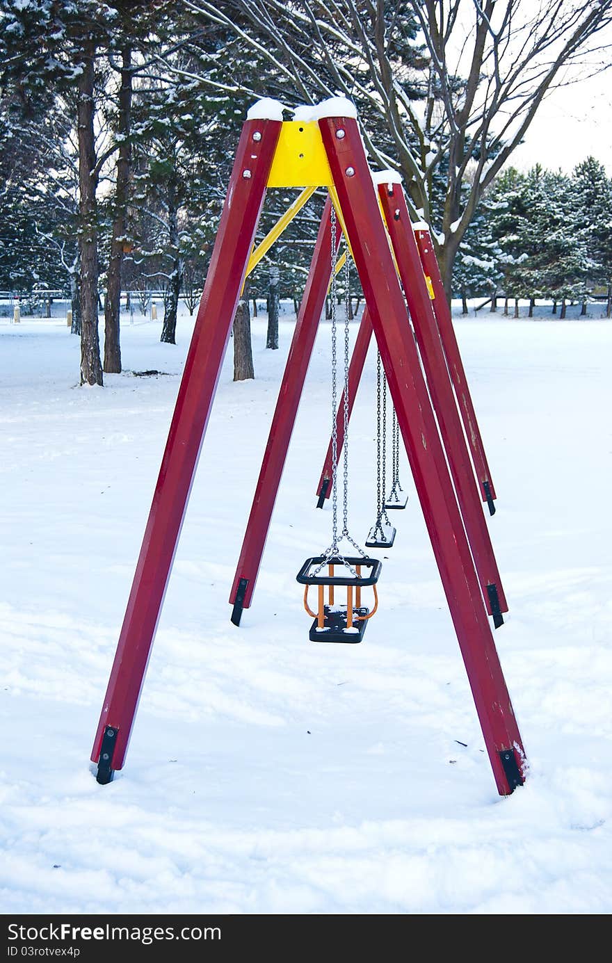 An empty children swings construction in a winter, snowy park. An empty children swings construction in a winter, snowy park