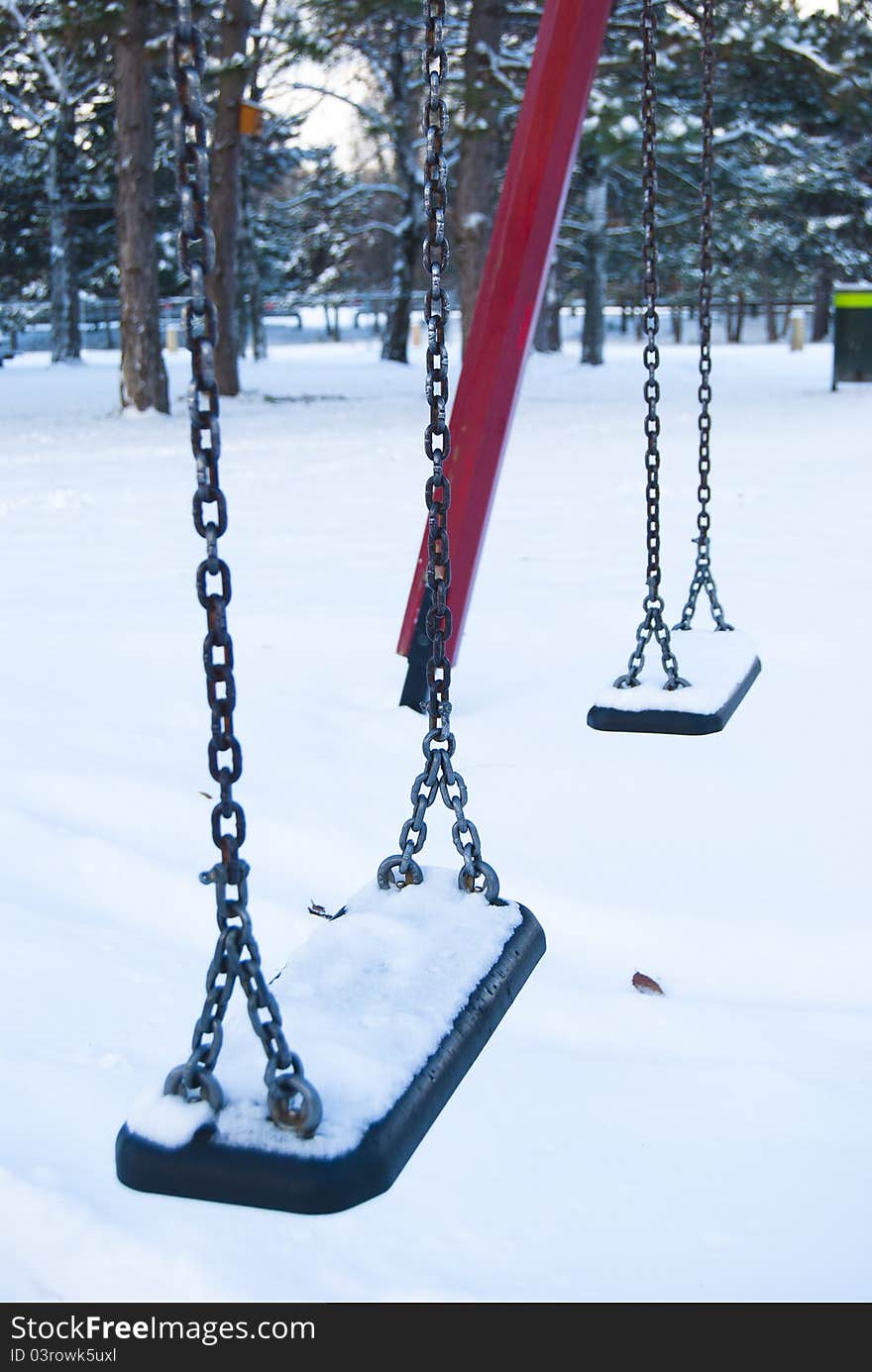 Empty children swings construction in a winter, snowy park. Empty children swings construction in a winter, snowy park