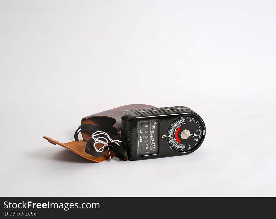 An antique photographers light meter and case on an easily removable light grey background. An antique photographers light meter and case on an easily removable light grey background