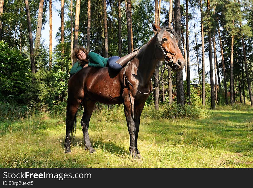 Smiling girl lies on horseback and coomunicats with her horse. Smiling girl lies on horseback and coomunicats with her horse