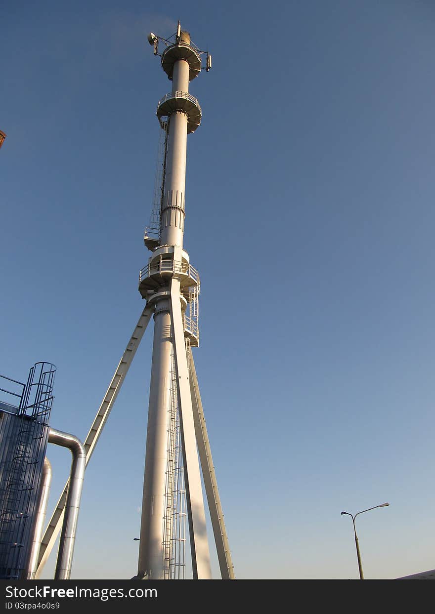 Metal chimney with antennas on the background of blue sky