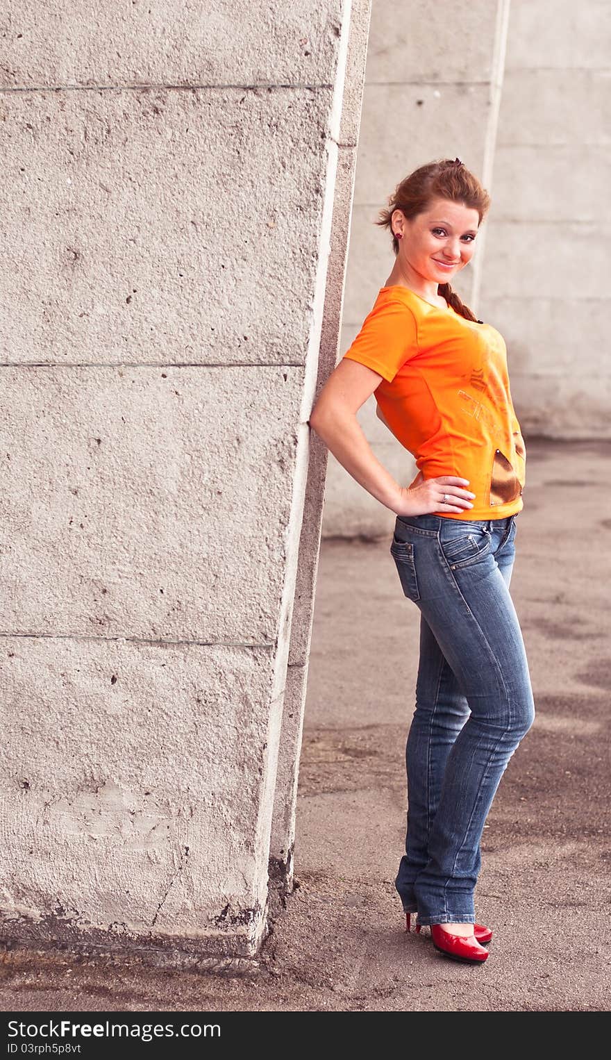 Full lenght shot of young woman against concrete wall. Full lenght shot of young woman against concrete wall