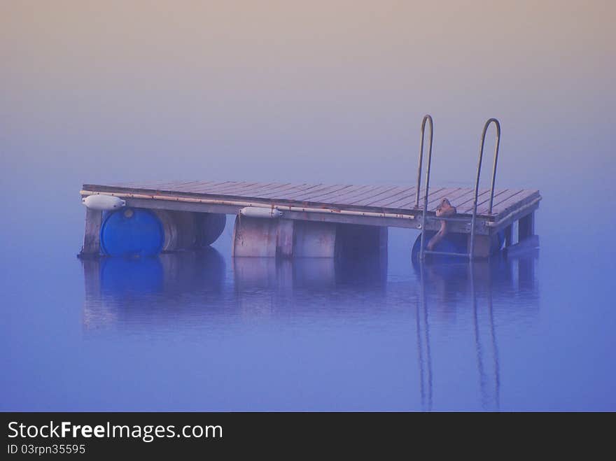 Dock floating on a glassy lake in the misty morning. Dock floating on a glassy lake in the misty morning