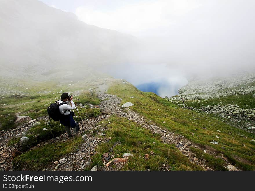 Hiker taking photos at Capra lake in Fagaras mountains, Romania