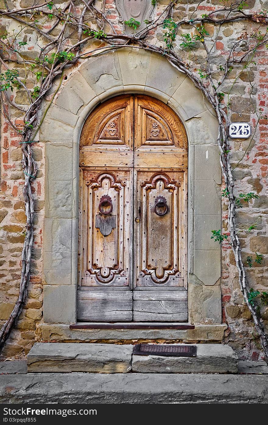 Old wooden door and brick wall in Tuscan village