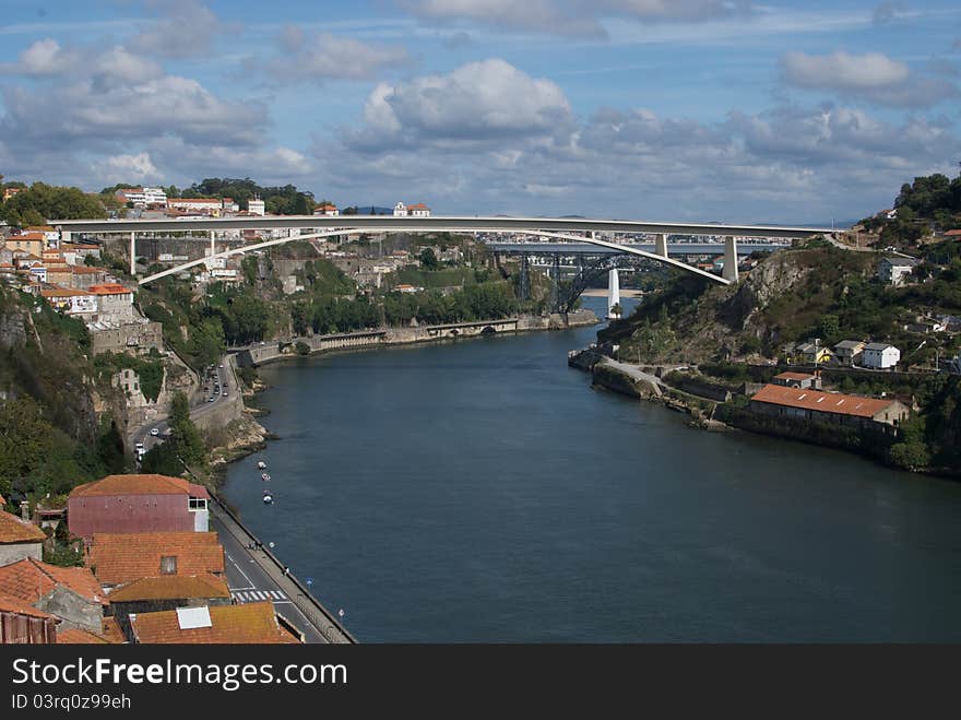 Porto, a city named for its importance as a shipping port in Portugal. A white bridge arcs over the main river of the city. Porto, a city named for its importance as a shipping port in Portugal. A white bridge arcs over the main river of the city.