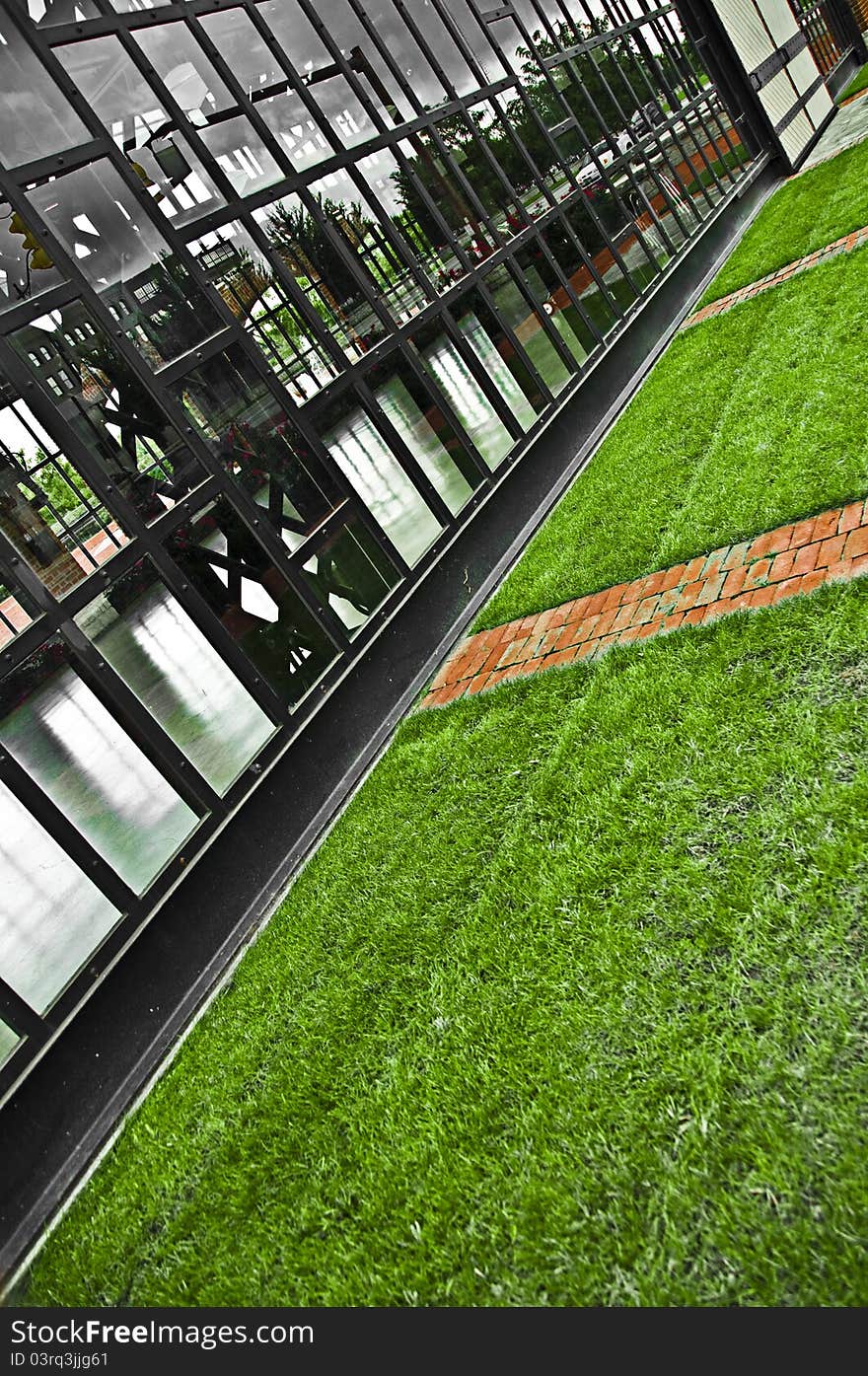 A photo of a glass wall with steal beams, and clean cut grass. A photo of a glass wall with steal beams, and clean cut grass.