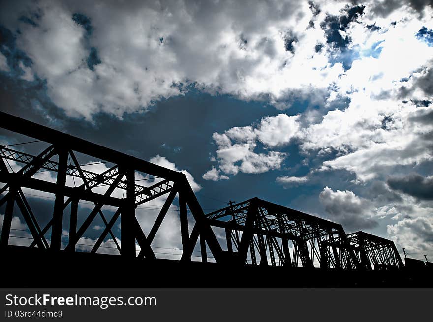 A bridge silo-wet with the sky and clouds in the background.