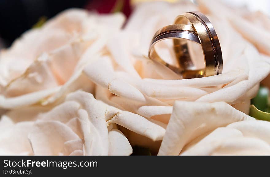 Wedding gold rings lie on a bunch of flowers for the bride