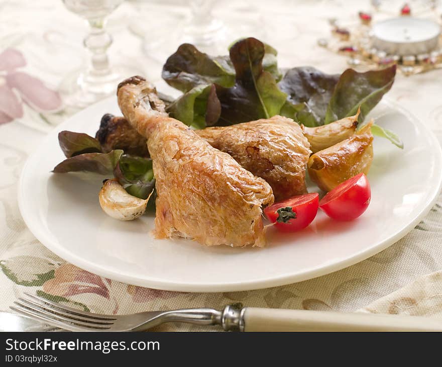 Roasted chicken legs with fresh tomato and lettuce for Christmas dinner. Selective fous