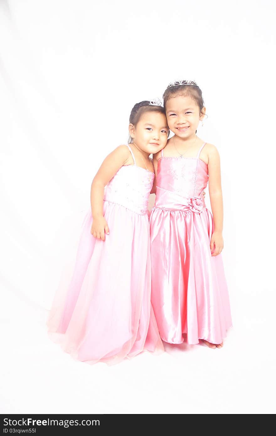 Two asian girls in pink clothes with crowns posing and smiling. Two asian girls in pink clothes with crowns posing and smiling