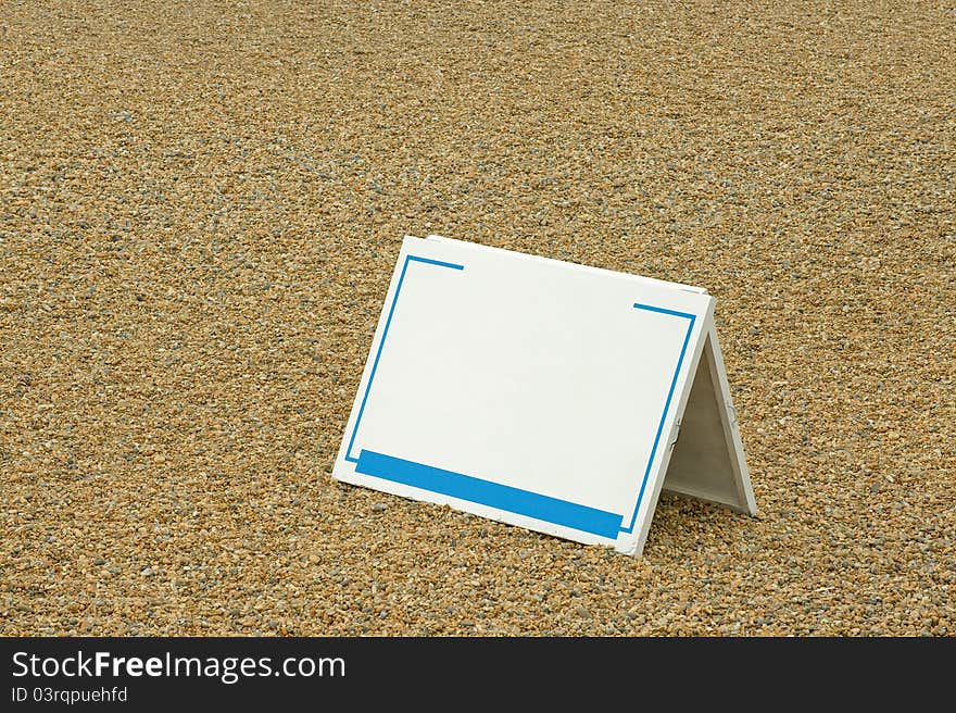 Blank sign copy-space template on a pebbled beach