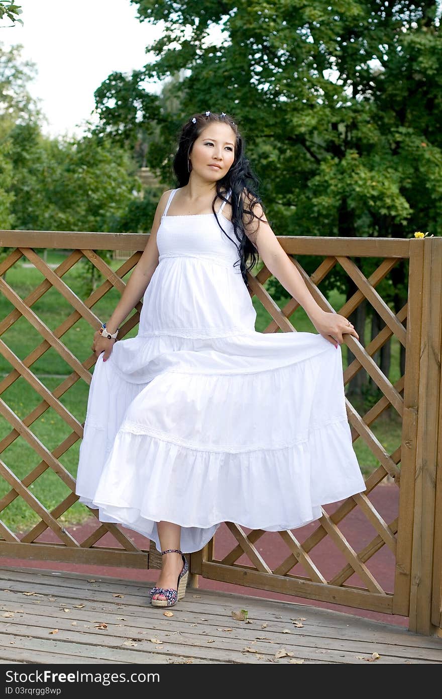 Beautiful pregnant girl walking in park in summer