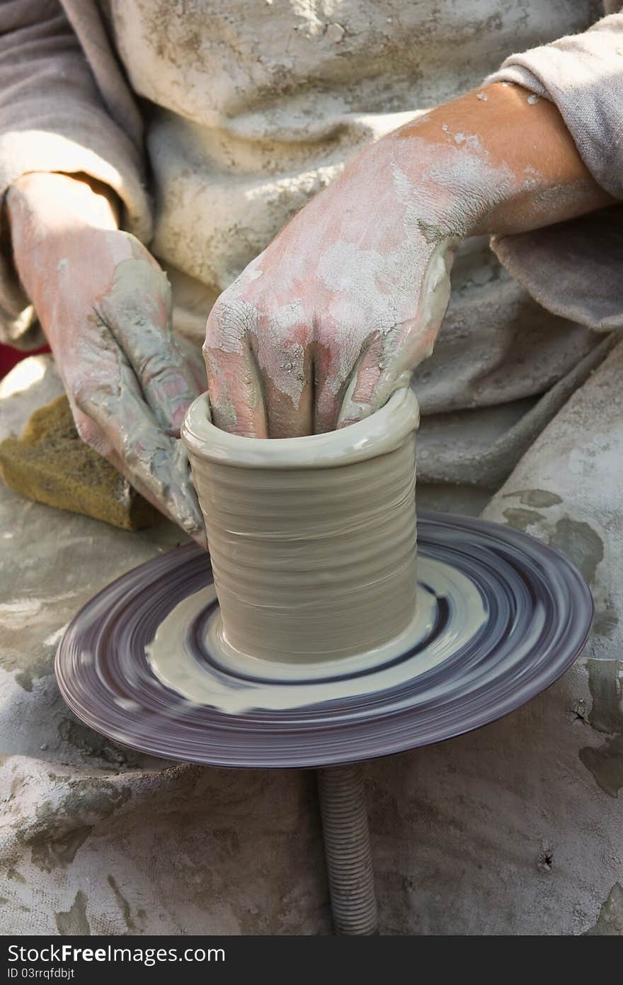 Potter makes a jug out of clay on potter's wheel.