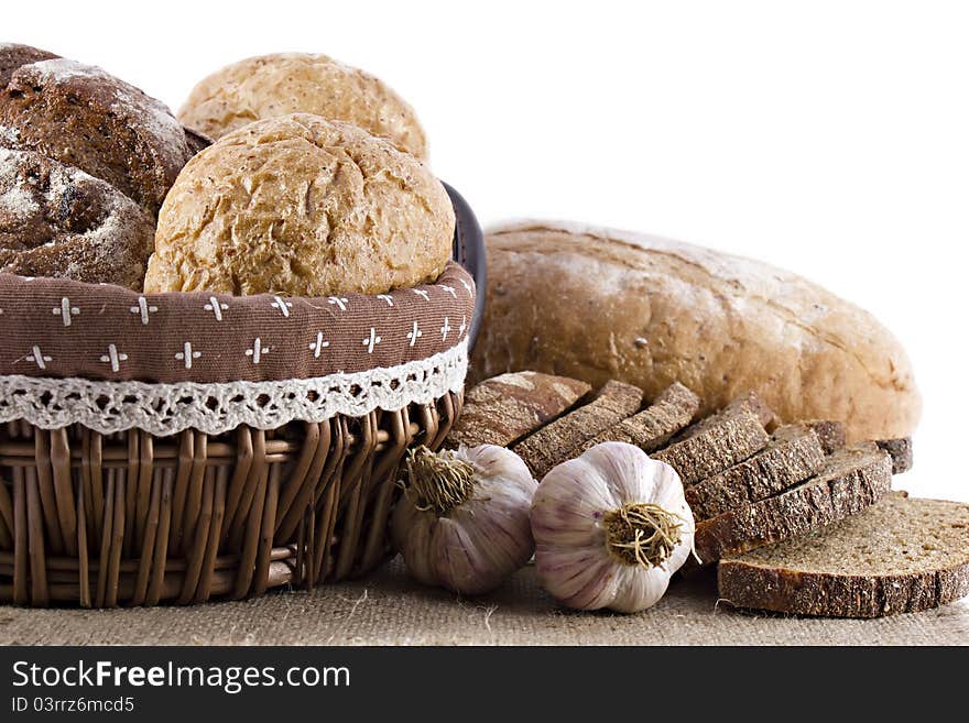 Loaves of bread and garlic over white background