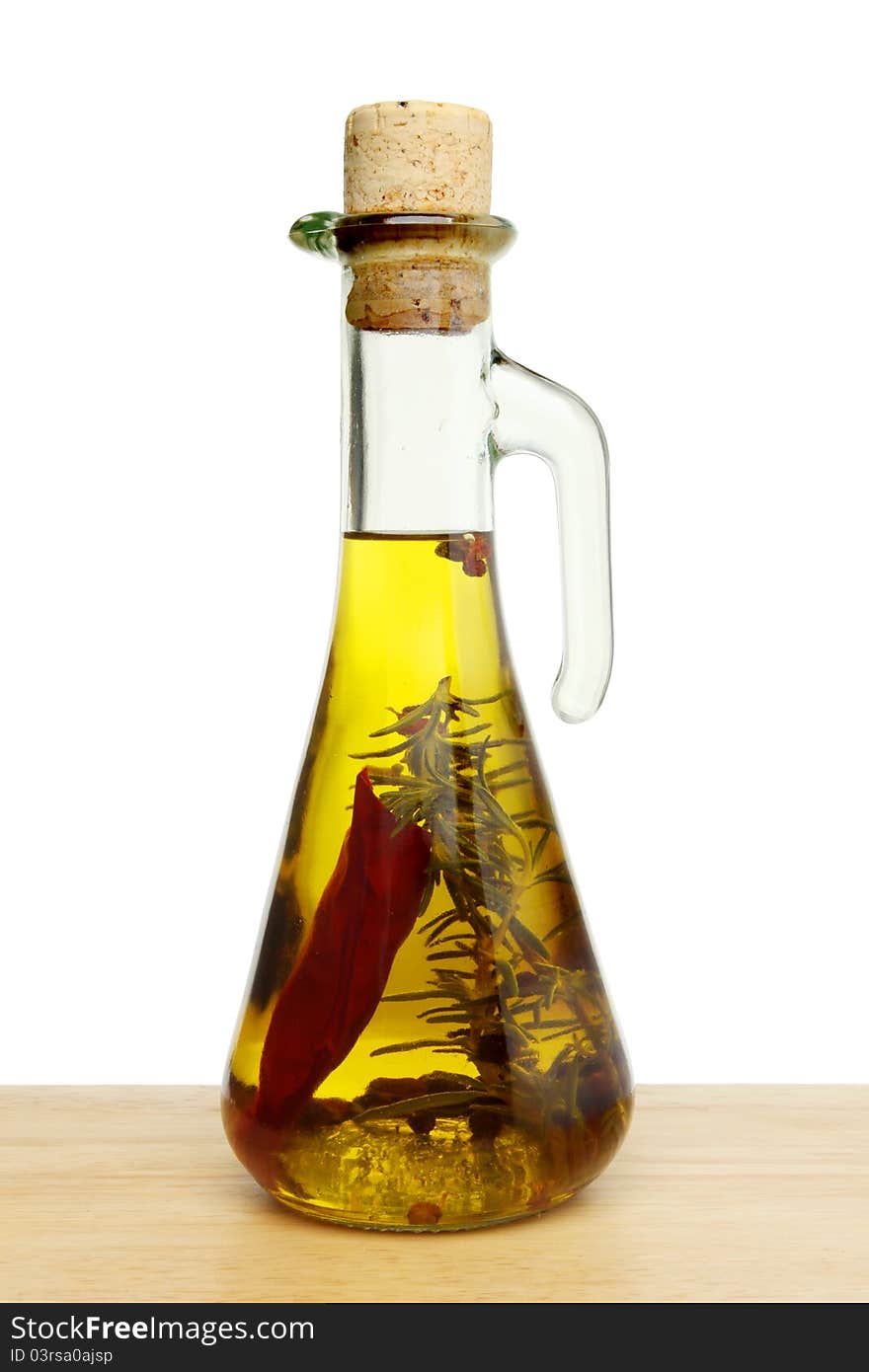 Flavoured olive oil in a glass jar on wood against a white background. Flavoured olive oil in a glass jar on wood against a white background