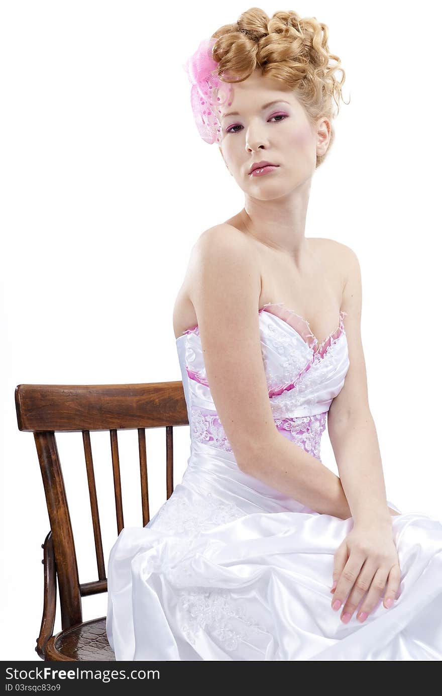 Beautiful girl in wedding dress on the chair isolated on white