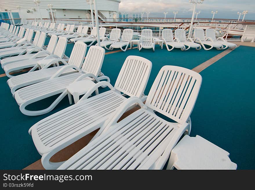 Many sun tanning beach chairs on top deck of cruise ship. Many sun tanning beach chairs on top deck of cruise ship.