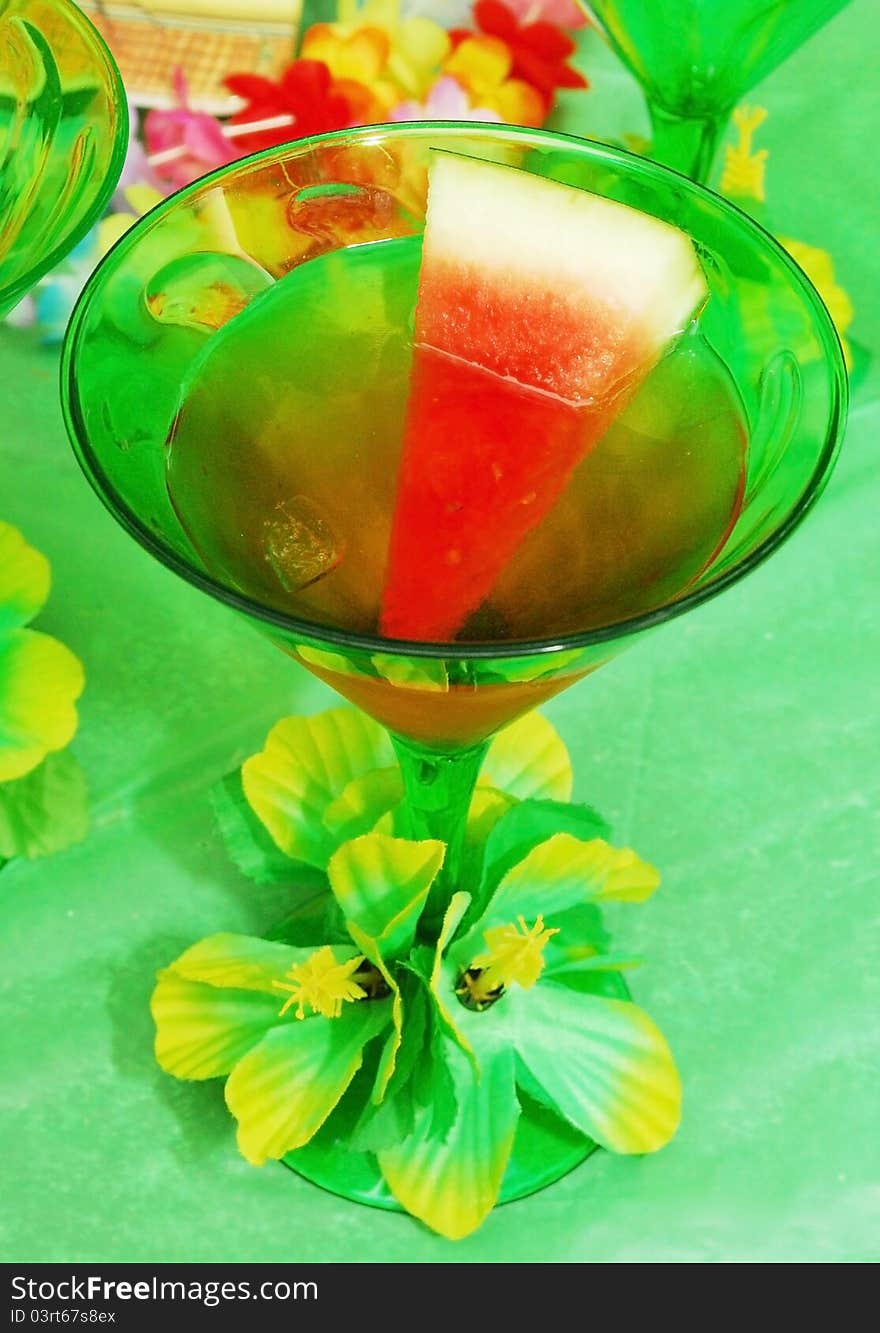 A cup of watermelon martini in green glass with flower.