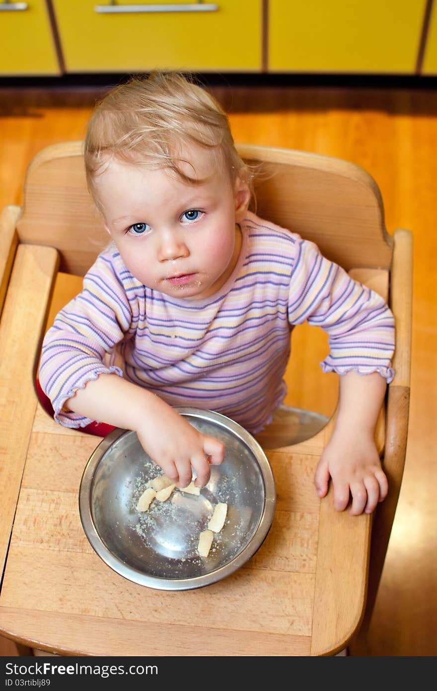 A boy sits in a chair and eat corn sticks. A boy sits in a chair and eat corn sticks