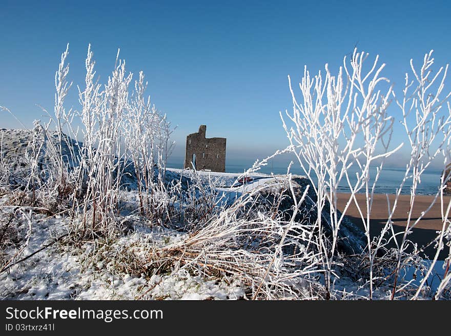 A seasonal snow covered view of atlantic ocean and ballybunion castle beach and cliffs on a frosty snow covered winters day. A seasonal snow covered view of atlantic ocean and ballybunion castle beach and cliffs on a frosty snow covered winters day