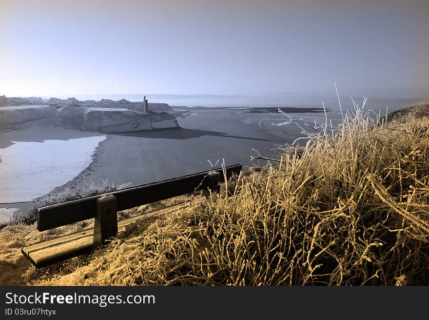 A seasonal snow covered view of atlantic ocean, beach and ballybunion castle with a bench on a frosty snow covered winters day. A seasonal snow covered view of atlantic ocean, beach and ballybunion castle with a bench on a frosty snow covered winters day