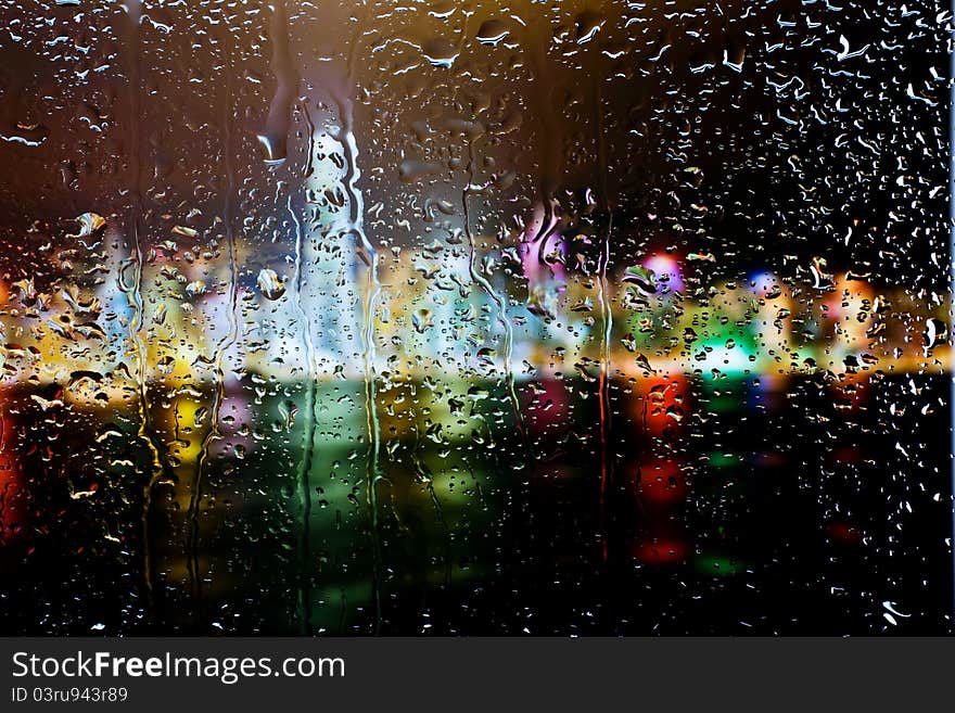 Background of Night city through wet window, Raindrops on the window at Night. Background of Night city through wet window, Raindrops on the window at Night