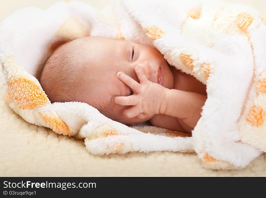 Baby lying and holding his head.