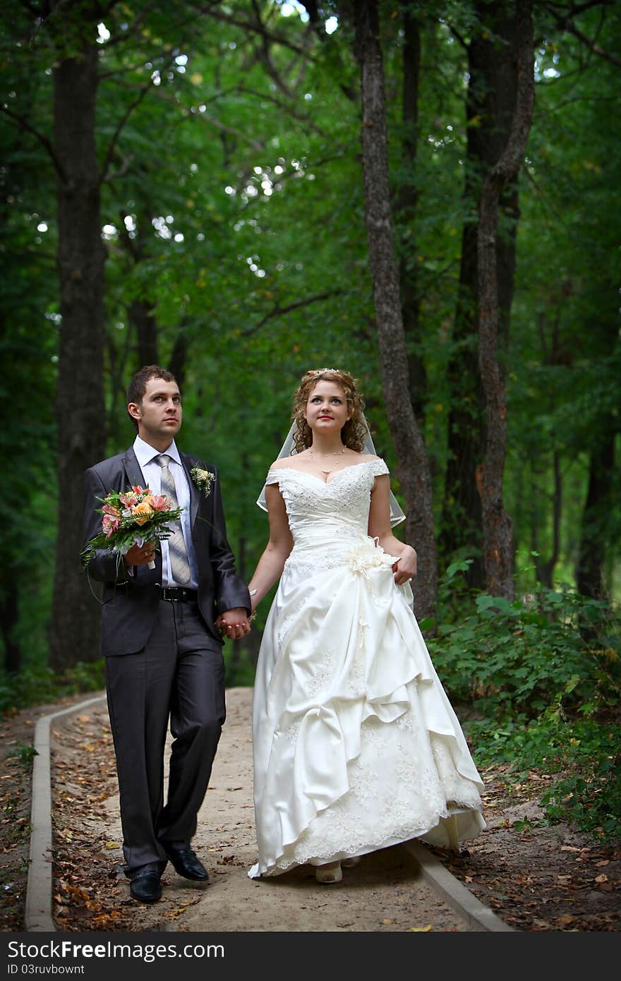 Bride and groom walking in forest