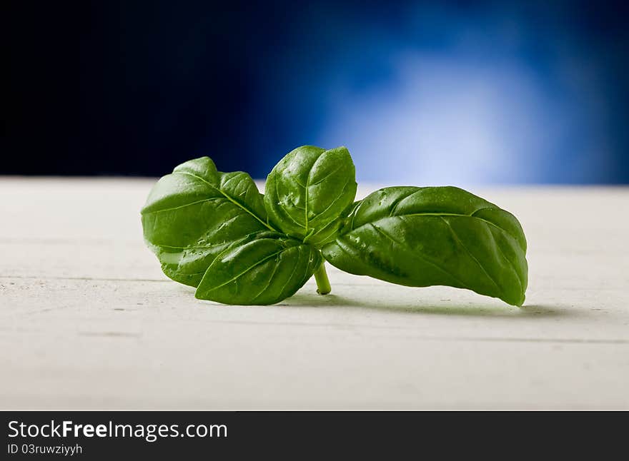 Basil leaves on wooden table highlighted by spot