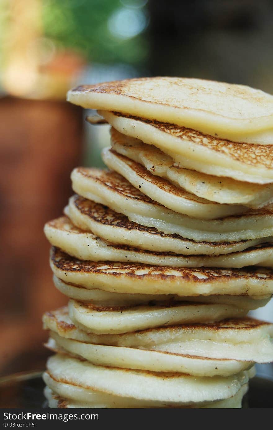 High pile of thick russian pancakes for breakfast. Natural light, green background. High pile of thick russian pancakes for breakfast. Natural light, green background