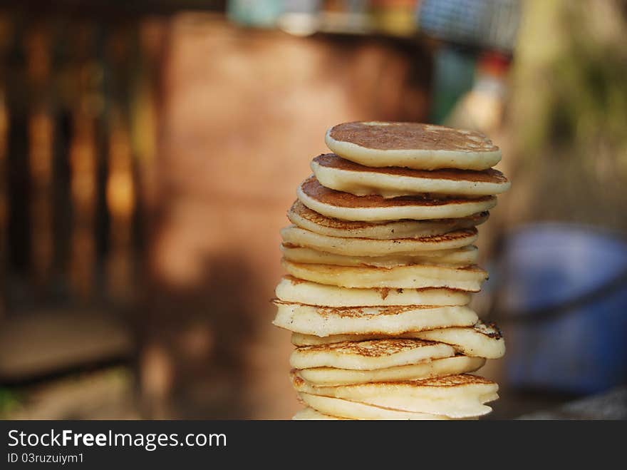 High pile of thick russian pancakes for breakfast. Natural light, green background. High pile of thick russian pancakes for breakfast. Natural light, green background