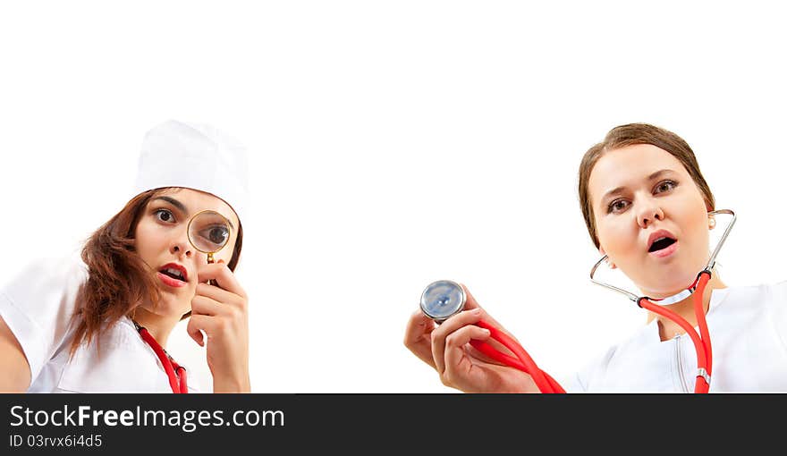 Two very surprised nurse doing a medical examination. One looks through a magnifying glass, the other holding a stethoscope. Two very surprised nurse doing a medical examination. One looks through a magnifying glass, the other holding a stethoscope