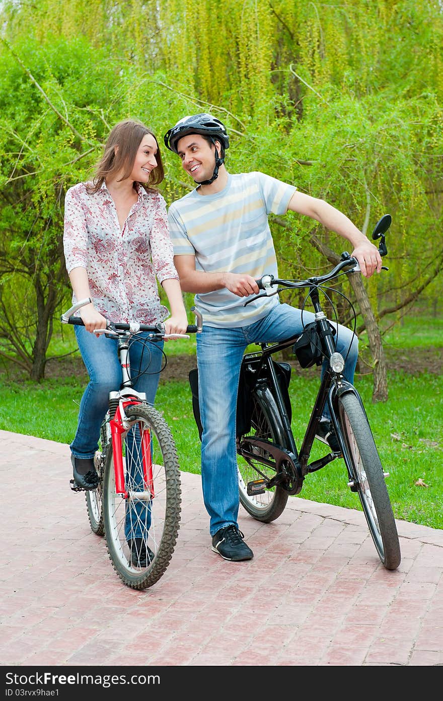 Happy young couple riding bicycles in a park