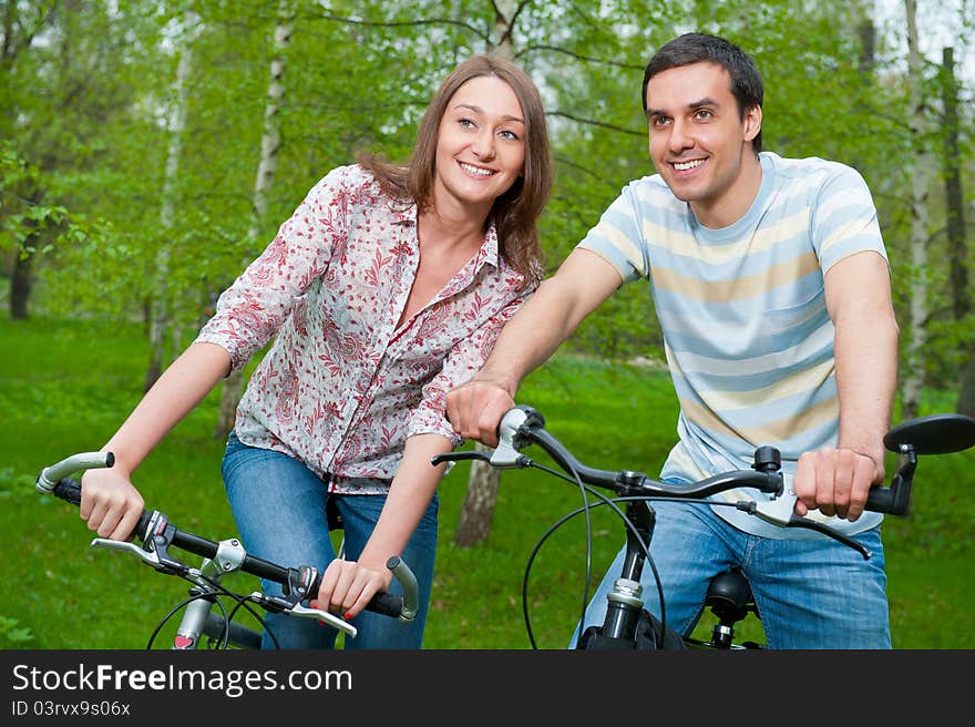 Happy young couple riding bicycles in a park