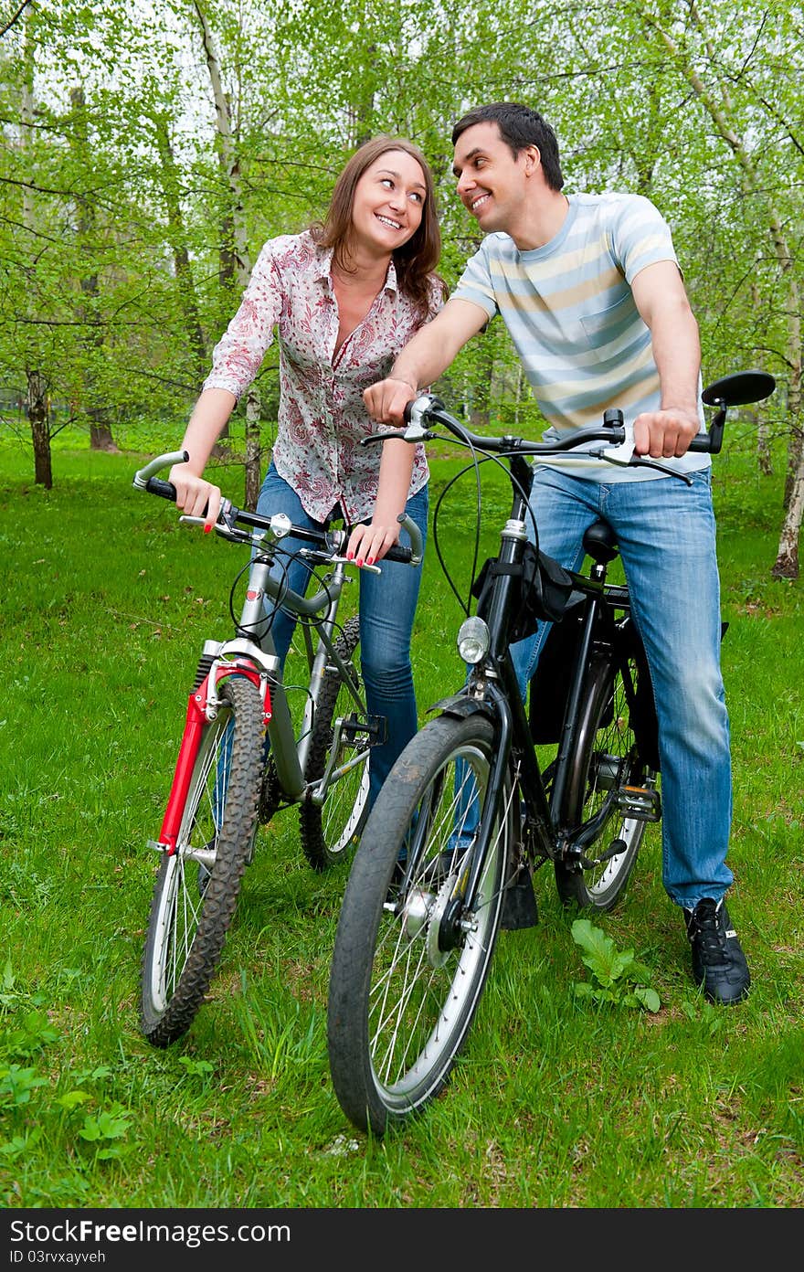 Happy young couple riding bicycles in a park