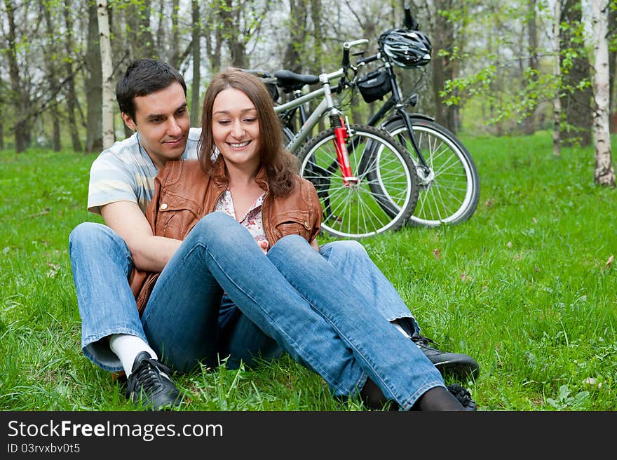 Young couple resting in a park, bicycles on background