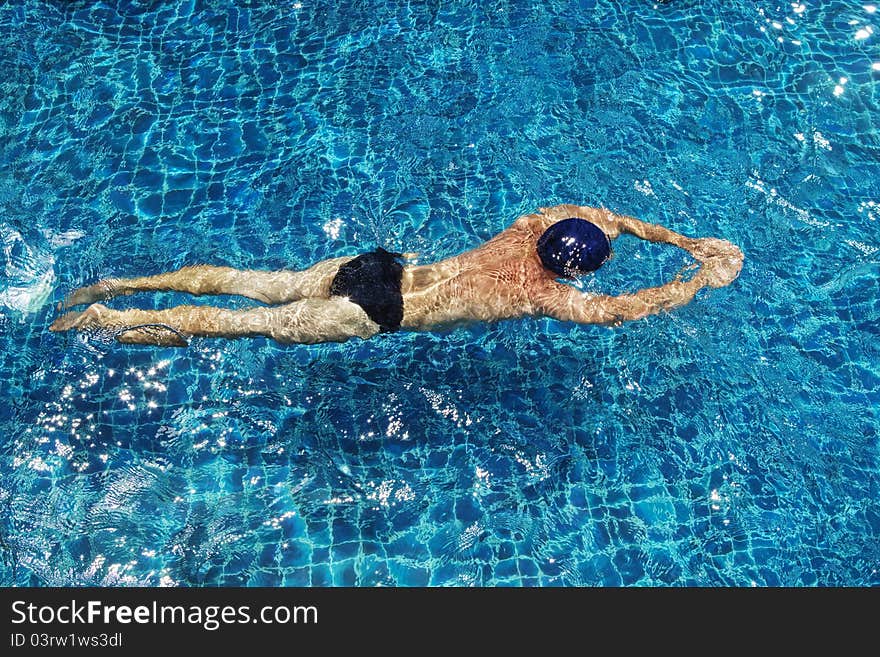 View of nice young man swimming in pool. View of nice young man swimming in pool