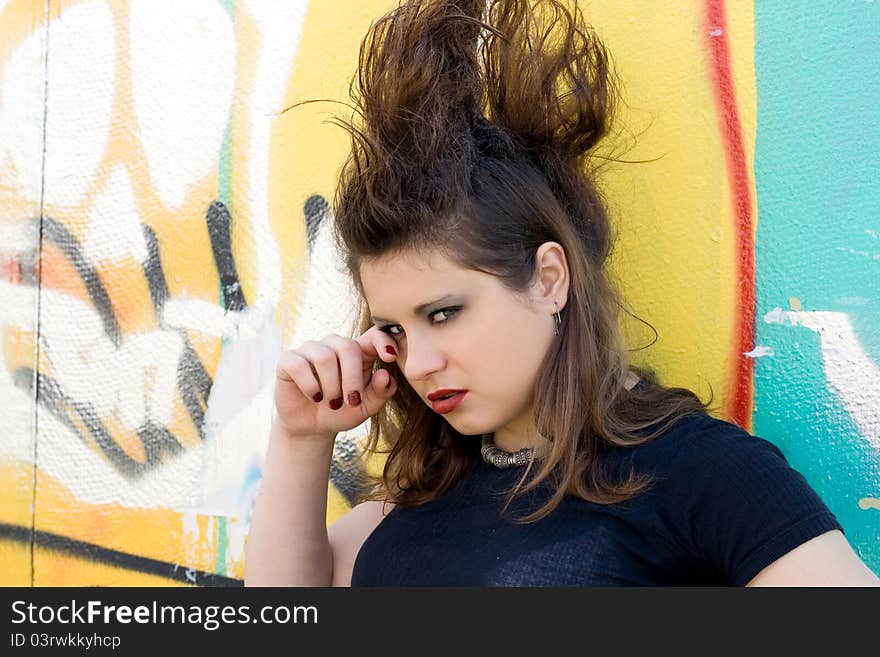 Crying punk girl standing in front of a graffiti wall