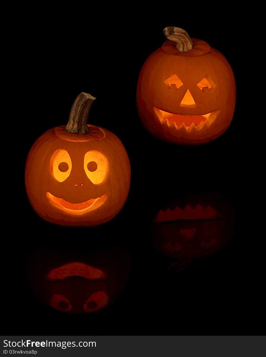 Two smiling jack-o lanterns with reflection on a black background. Two smiling jack-o lanterns with reflection on a black background