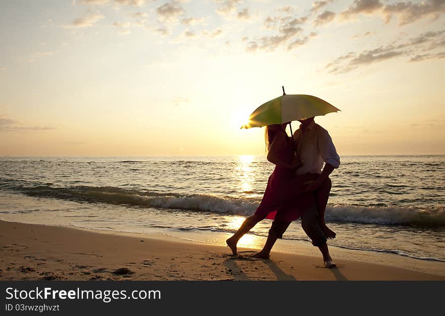 Couple kissing at the beach in sunset.