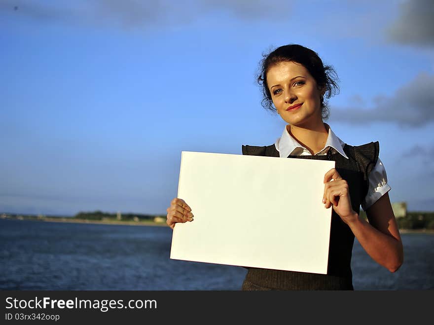 Beautiful girl holding blank paper. sea on the background